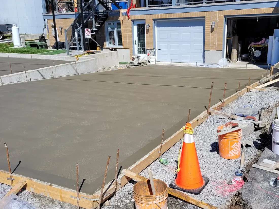 Dalle de béton fraîchement coulée devant un garage résidentiel